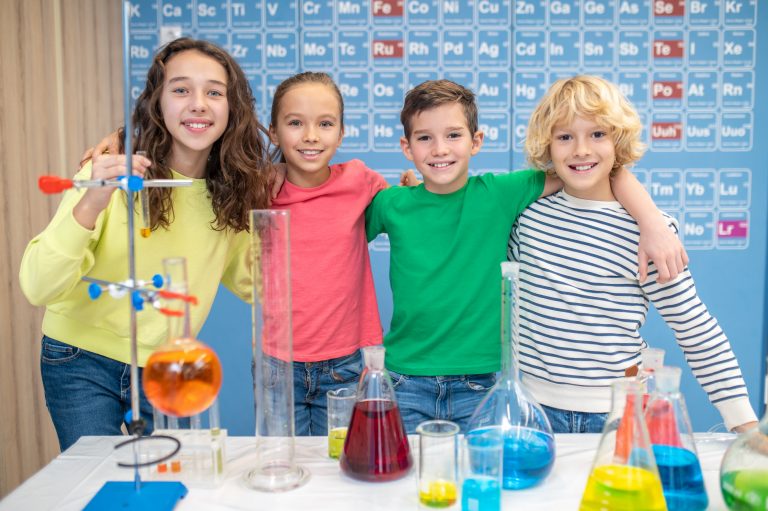 Children hugging looking at camera in chemistry class