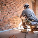 A builder works with a drill at a construction site.