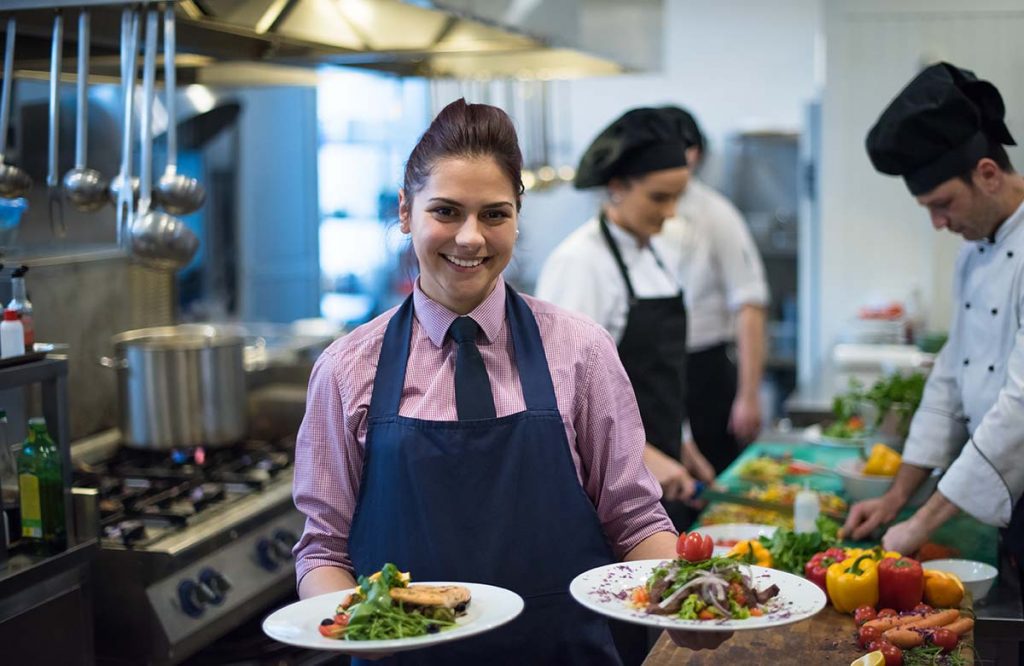 young waitress showing dishes of tasty meals